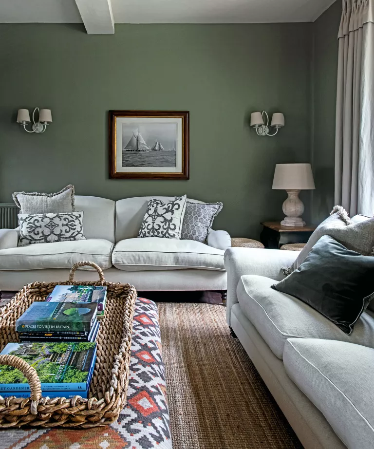Beyaz kanepe ve sisal halı ile yeşil oturma odası