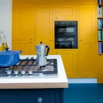 beyaz tezgahlı sarı mutfak, mavi le creuset güveç kabı ve ankastre mikrodalga