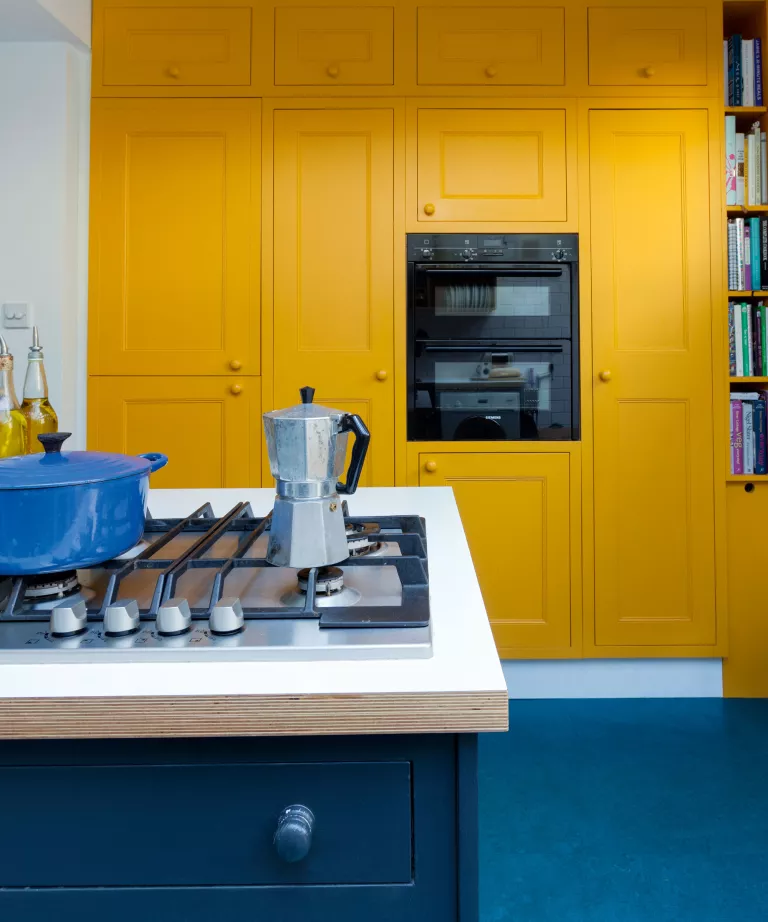 beyaz tezgahlı sarı mutfak, mavi le creuset güveç kabı ve ankastre mikrodalga